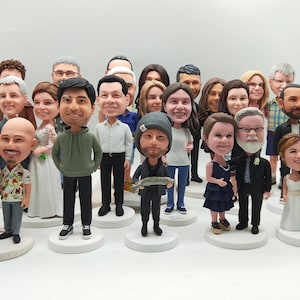 May include: A collection of custom bobblehead figurines featuring various individuals in diverse outfits, including wedding attire, casual clothing, and formal wear. Each figure stands on a circular white base, showcasing detailed facial features.