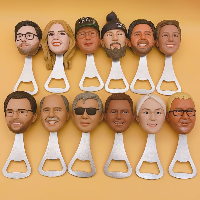 May include: A collection of personalized bottle openers featuring sculpted faces. Each opener has a unique face with varying hairstyles, glasses, and expressions. The openers are made of silver metal and are arranged on a yellow background.