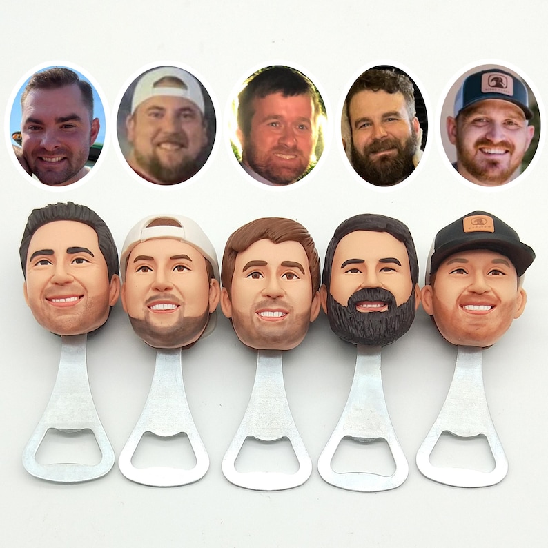 May include: A collection of five bottle openers, each featuring a smiling male face as the handle. The faces are painted with realistic skin tones and hair colors. The bottle openers are made of silver metal and are arranged in a row.
