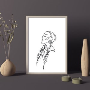 May include: Line art print of a woman with long braids and an earring. The woman is looking up and to the right. The print is in black and white and is framed in a white frame.