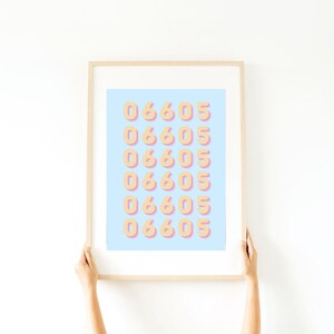 May include: A framed print with a light blue background and a repeating pattern of the numbers 06605 in a peach colour with a pink outline.