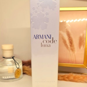May include: A white box with a blue floral design and the text "ARMANI code luna" in blue. The text "eau de toilette vaporisateur" and "GIORGIO ARMANI" are also printed on the box.