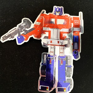 May include: A silver sticker of Optimus Prime, a red and blue robot, in his truck form. The sticker is a popular character from the Transformers franchise.