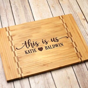 May include: Personalized bamboo cutting board with the text "This is us Katie Baldwin" and a heart symbol.