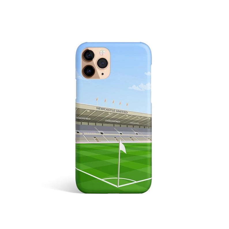 Może przedstawiać: Etui na telefon z wzorem stadionu piłkarskiego z zielonym boiskiem i białą flagą. Na stadionie widnieje napis "NEWCASTLE UNITED". Etui ma czarny wystający aparat z trzema obiektywami.