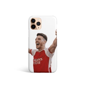 May include: White iPhone case with a photo of a soccer player in a red and white jersey celebrating with his arms raised. The jersey has the text "Fly Better" and a sponsor logo.