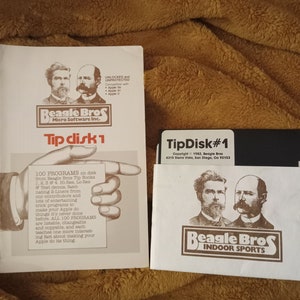 Könnte beinhalten: Eine weiße Diskette mit dem Text "TipDisk#1" und "Beagle Bros Indoor Sports" in brauner Schrift. Die Diskette ist von einem weißen Rand mit dem Text "Copyright © 1982, Beagle Bros 4315 Siena Vista, San Diego, Ca 92103" umgeben.