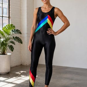 May include: A black sleeveless unitard featuring a scoop neckline and a fitted silhouette. The garment is accented with diagonal stripes in bright blue, yellow, and red across the chest and a matching striped pattern on the lower left leg.