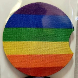 May include: Two round rainbow-colored coasters with a cut-out for a beverage. The coasters are made of a fabric material and have a black backing.