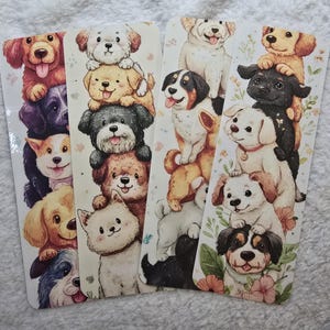 May include: Four dog-themed bookmarks featuring stacks of adorable cartoon puppies in various colors. Each bookmark has a different arrangement of dogs, with some designs including floral accents. The bookmarks are rectangular and printed on glossy paper.