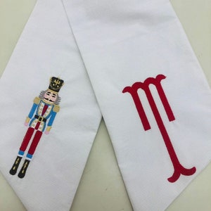 White wreath sash with blue nutcracker embroidery design and monogram