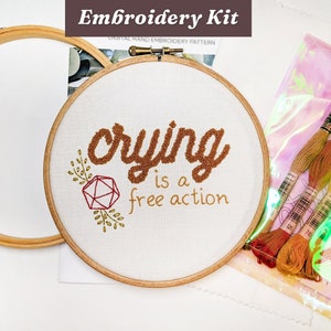 May include: Embroidery kit with a wooden hoop and the phrase "crying is a free action" stitched in brown thread. Includes embroidery floss in shades of orange and yellow, and a digital hand embroidery pattern.