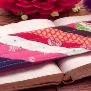 May include: A colorful fabric bookmark with a red, white, and blue pattern. The bookmark is lying on top of a closed book.