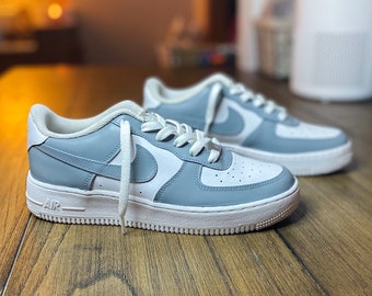 May include: A pair of white and light blue sneakers with a white swoosh logo and the word "AIR" on the side.