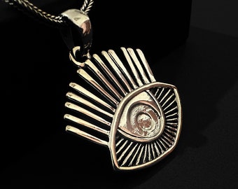 May include: A silver eye pendant necklace with a detailed design of an eye with radiating lines. The pendant is on a silver chain.