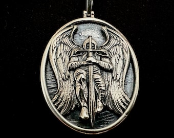 May include: Silver pendant featuring a detailed sculpture of an angel holding a sword. The angel has large wings and is depicted in a protective stance.