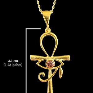 Op de afbeelding: Gouden ketting met hanger in de vorm van een Ankh met een roze oog van Horus bedel. De hanger is 3,1 cm lang.