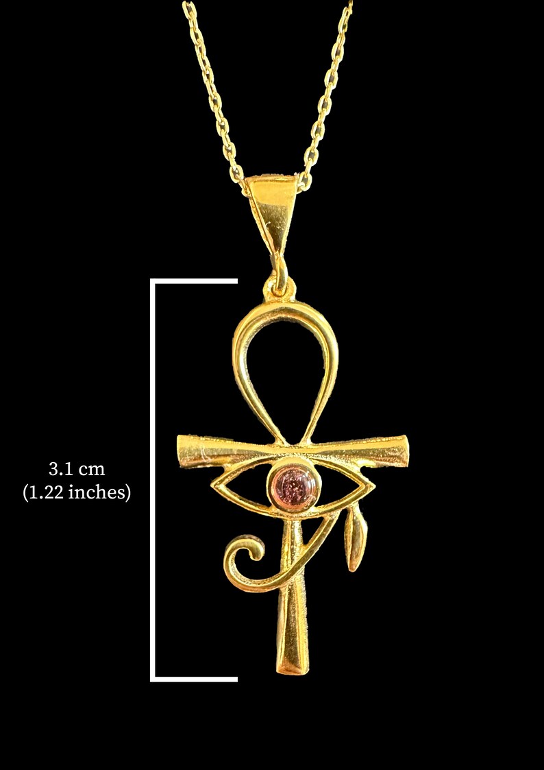 Op de afbeelding: Gouden ketting met hanger in de vorm van een Ankh met een roze oog van Horus bedel. De hanger is 3,1 cm lang.