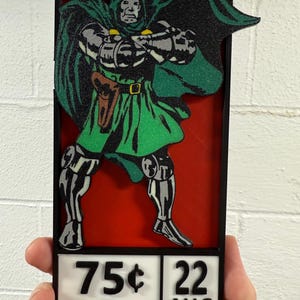 May include: A rectangular wall plaque featuring a raised, glittery green and silver depiction of Doctor Doom against a solid red background. Below the figure, a white panel displays the text 75 cents, 22 AUG, and 02686 in black lettering.