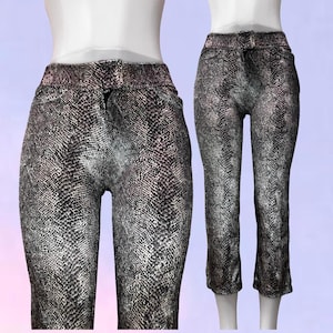 May include: High-waisted trousers featuring a detailed black and grey snakeskin pattern. The garment has a fitted silhouette with a straight leg cut, a standard waistband with belt loops, and a front fly closure, displayed on a mannequin form.