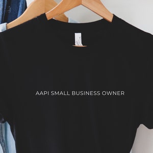 May include: Black t-shirt with the text "AAPI Small Business Owner" printed in white on the front.