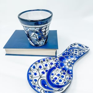 May include: Blue and white ceramic spoon rest and a small cup with a floral design.