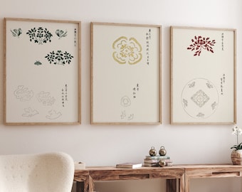 May include: Three framed prints with black and white illustrations of flowers and plants. The prints are hung on a white wall above a wooden table with a white armchair and a small wooden table with a book on top.