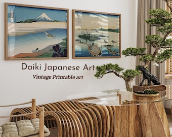 May include: Two framed Japanese woodblock prints depicting scenes of Mount Fuji and boats on a body of water. The prints are hanging on a white wall above a wooden table and chairs. The text "Daiki Japanese Art Vintage Printable art" is below the prints.