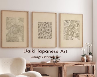 May include: Three framed prints of vintage Japanese art with black and white floral patterns. The prints are hanging on a white wall above a wooden table with a white chair. The text "Daiki Japanese Art Vintage Printable Art" is below the prints.