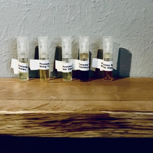 May include: Five perfume sample vials with clear spray tops and white labels. The labels read "Phronema Inoles", "Phronema Being-T", "Phronema New Vala", "Phronema Monoliths", and "Phronema Pr Niral Hist". The vials contain liquids of different colours.