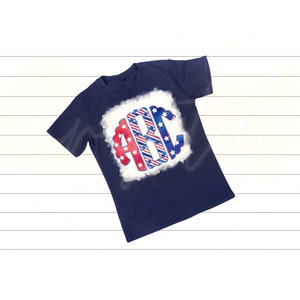 K&ouml;nnte beinhalten: Ein marineblaues T-Shirt mit einem wei&szlig;en Wolken-Design, das die Buchstaben "ABC" in rot-wei&szlig;-blauen Streifen mit wei&szlig;en Sternen zeigt.