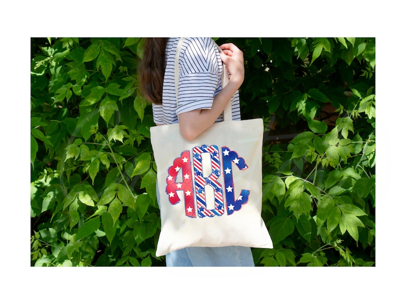 K&ouml;nnte beinhalten: Eine wei&szlig;e Canvas-Tragetasche mit einem rot-wei&szlig;-blauen Monogramm-Design mit den Buchstaben "ABC". Das Monogramm ist von einem gewellten Rand umgeben. Die Tasche wird von einer Person getragen, die ein gestreiftes Hemd und eine blaue Jeans tr&auml;gt.