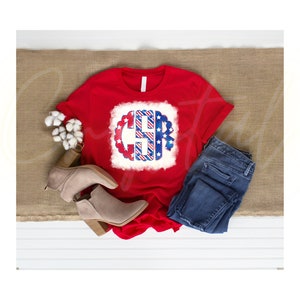 K&ouml;nnte beinhalten: Rotes T-Shirt mit einem wei&szlig;en, blauen und roten Monogramm-Design mit Sternen und Streifen. Das Monogramm ist der Buchstabe "C".