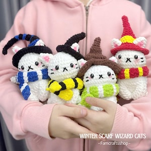 May include: Four white crocheted cat plushies wearing witch hats and colorful scarves. The cats are holding hands and have black eyes and a stitched 'x' for a mouth. The text 'WINTER SCARF WIZARD CATS -Famcraftshop-' is at the bottom of the image.