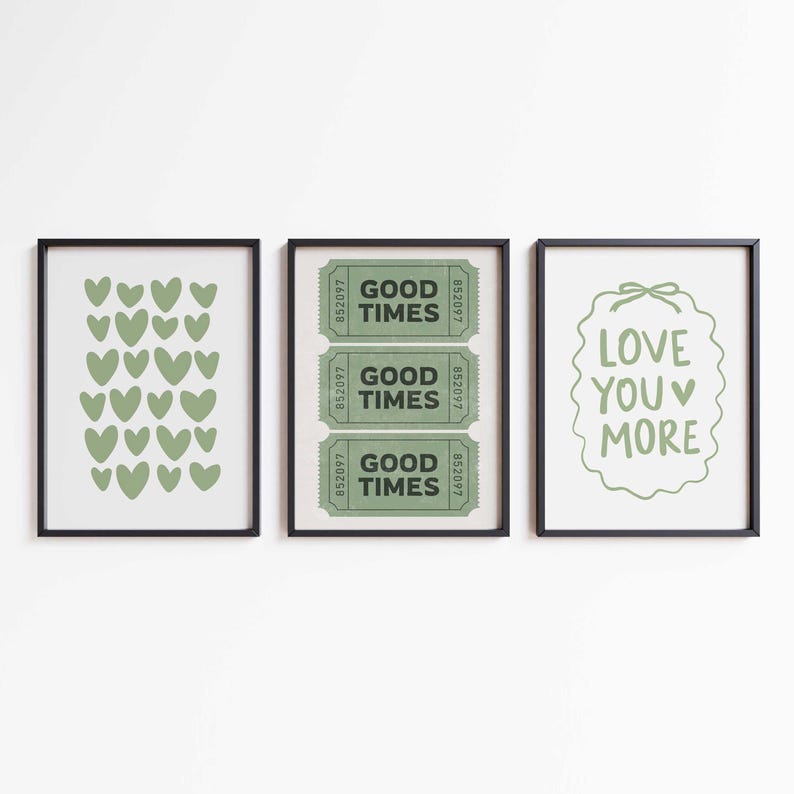 May include: Three framed art prints. The left print features green hearts. The center print displays three green "Good Times" tickets. The right print has the text "Love You More" in green. All prints are in black frames.