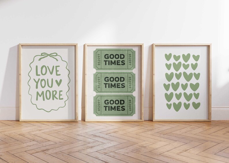 May include: Three framed art prints with light wood frames. The left print says "LOVE YOU MORE" in green. The middle print has three green "GOOD TIMES" tickets. The right print features green heart shapes.