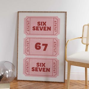 Puede incluir: Impresión enmarcada con tres boletos rosas con los números "67" y "SIX SEVEN" en fuente rojo oscuro. Los boletos tienen un diseño vintage con números de serie y se muestran sobre un fondo claro.