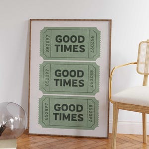 May include: A framed print featuring three green vintage-style tickets with the words "GOOD TIMES" in bold black letters. Each ticket has a unique serial number. The print is in a brown frame.