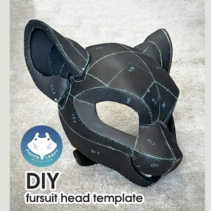 Puede incluir: Un patrón de cabeza de fursuit negro de bricolaje con un diseño de gato. La máscara tiene orejas grandes y un área para los ojos abierta. El patrón está marcado con líneas y letras. El texto "DIY fursuit head template" y un logotipo están incluidos.