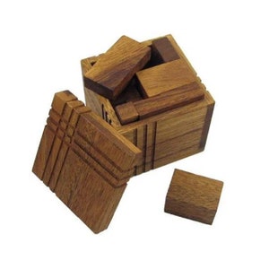 May include: A wooden puzzle box with a lid that opens to reveal a series of interlocking wooden pieces. The box is made of light brown wood and has a natural finish.
