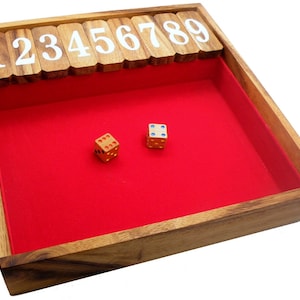 May include: Wooden game board with a red felt interior. The board has numbered tiles from 1 to 9. Two dice are on the felt, one is red and one is blue.