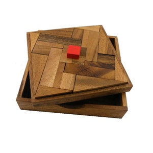 May include: A wooden puzzle box with a red square piece in the center of the lid. The lid is open and the box is made of light brown wood.