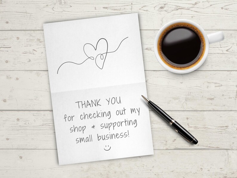 K&ouml;nnte beinhalten: Eine wei&szlig;e Karte mit einer handgeschriebenen Nachricht, die "THANK YOU for checking out my shop & supporting small business!" mit einem Smiley am unteren Rand lautet. Ein schwarzer Stift und eine wei&szlig;e Kaffeetasse befinden sich auf einer wei&szlig;en Holzoberfl&auml;che.