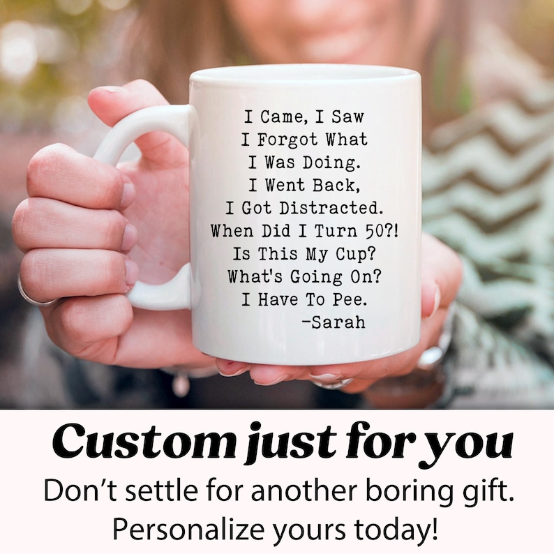 May include: White ceramic mug with a humorous poem about aging, including the text "I Came, I Saw, I Forgot What I Was Doing." The mug also includes the text "When Did I Turn 50?!" and "I Have To Pee." The mug is held by a person.