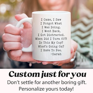 May include: White ceramic mug with a curved handle, featuring black text that reads "I Came, I Saw, I Forgot What I Was Doing... When Did I Turn 60?!" and the name "Sarah." The mug is held by a person. Below the mug, the text "Custom just for you" is visible.