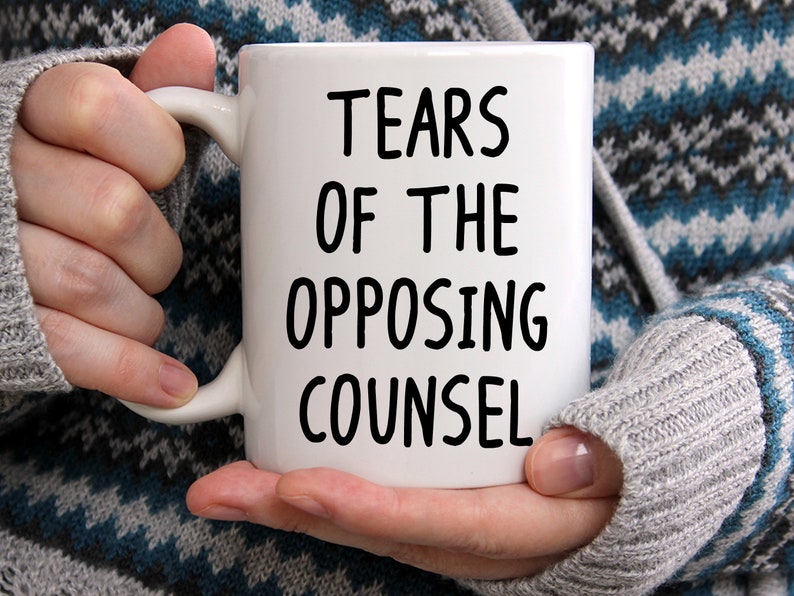 May include: White ceramic coffee mug with black text that reads "Tears of the Opposing Counsel".