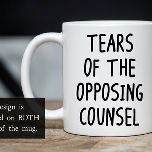 May include: White ceramic coffee mug with black text that reads "Tears of the Opposing Counsel".