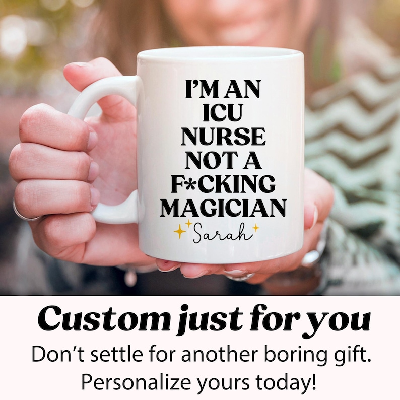 Może przedstawiać: Biały ceramiczny kubek z napisem "I'M AN ICU NURSE NOT A F*CKING MAGICIAN" w kolorze czarnym. Imię "Sarah" znajduje się pod tekstem, w czcionce skryptowej. Kubek jest trzymany przez osobę.