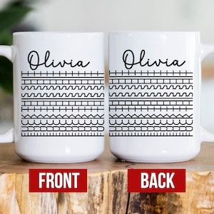 May include: White ceramic mug with the name "Olivia" in black script. The mug features a black geometric pattern with various shapes. The word "FRONT" is printed on a red rectangle. The back of the mug is also visible.