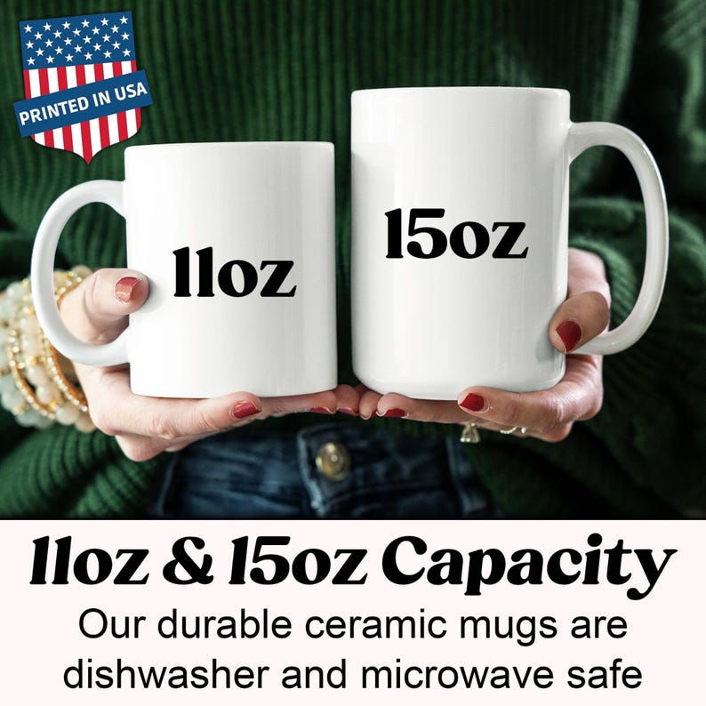 May include: Two white ceramic mugs, one labeled "11oz" and the other "15oz", are held in front of a green sweater. The mugs are part of a set, as indicated by the text "11oz & 15oz Capacity". The mugs are dishwasher and microwave safe.